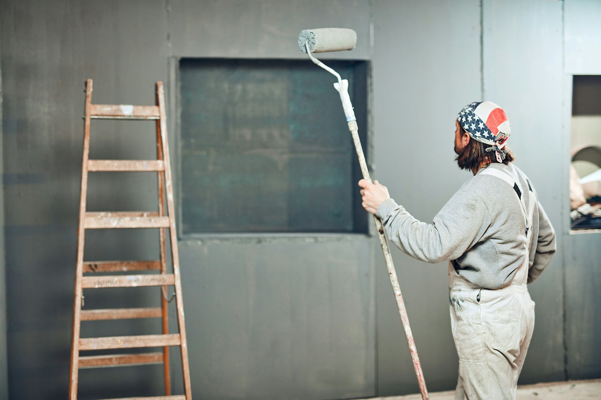 Professional painter rolling paint on a wall with modern equipment